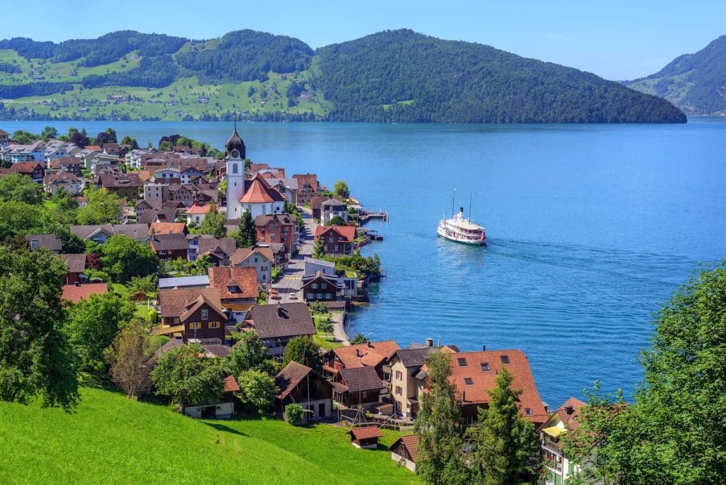 A boat sails near a typical village on Lake Lucerne in the Swiss Alps.