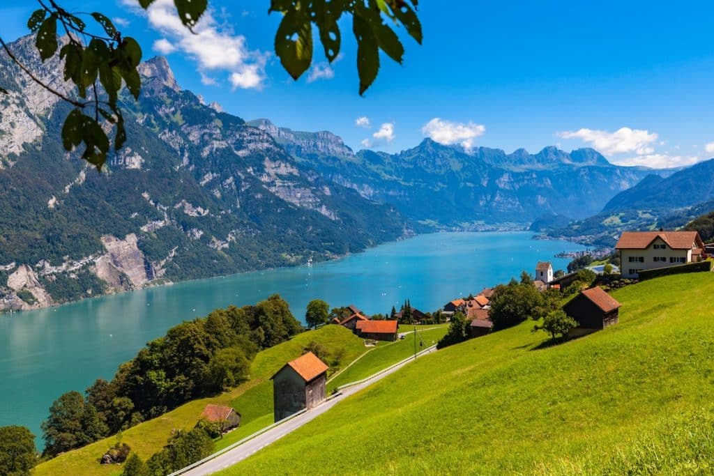 Panorama view Walensee (Walen) lake and the Alps on the hiking trail with green pasture in foreground from south side of the lake, Canton of Glarus, Switzerland.
