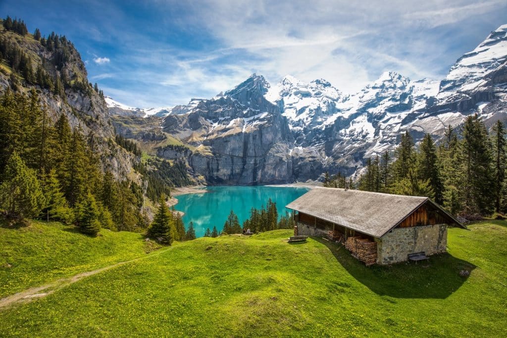 Amazing tourquise Oeschinnensee with waterfalls, wooden chalet and Swiss Alps, Berner Oberland, Switzerland.